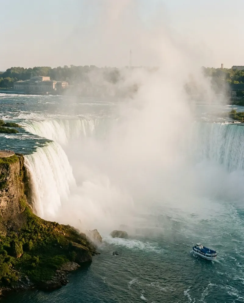 Niagara Falls with tour boat at its base surrounded by mist